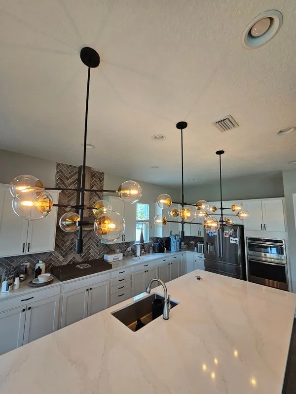 white kitchen with marble island and black globe-pendant chandeliers