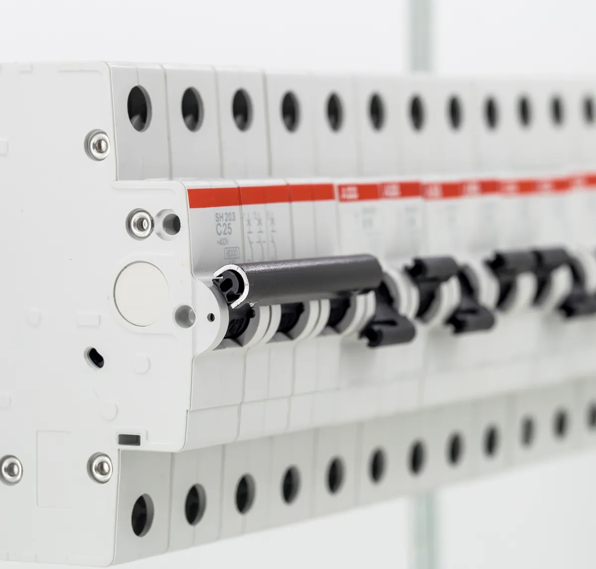 Close-up of a row of DIN-rail miniature circuit breakers, white with red bands, on a white background