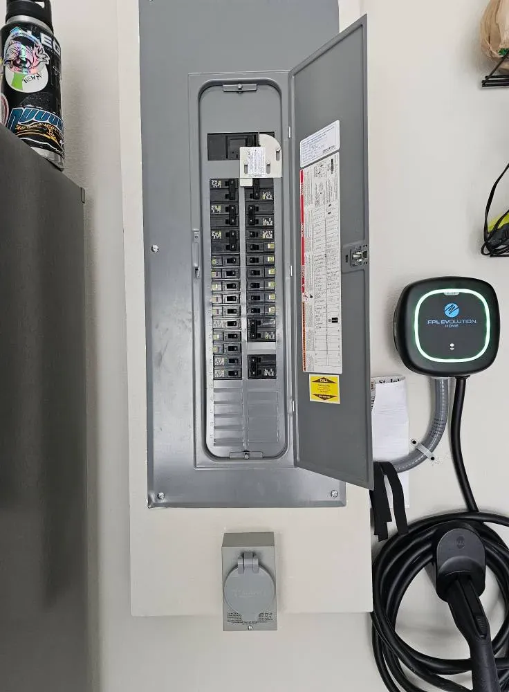 Open residential breaker panel with a wall-mounted EV charger