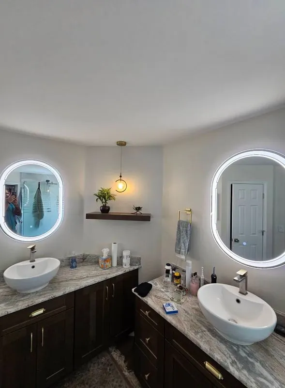 Bathroom double vanity with round backlit LED mirrors, vessel sinks and a pendant light