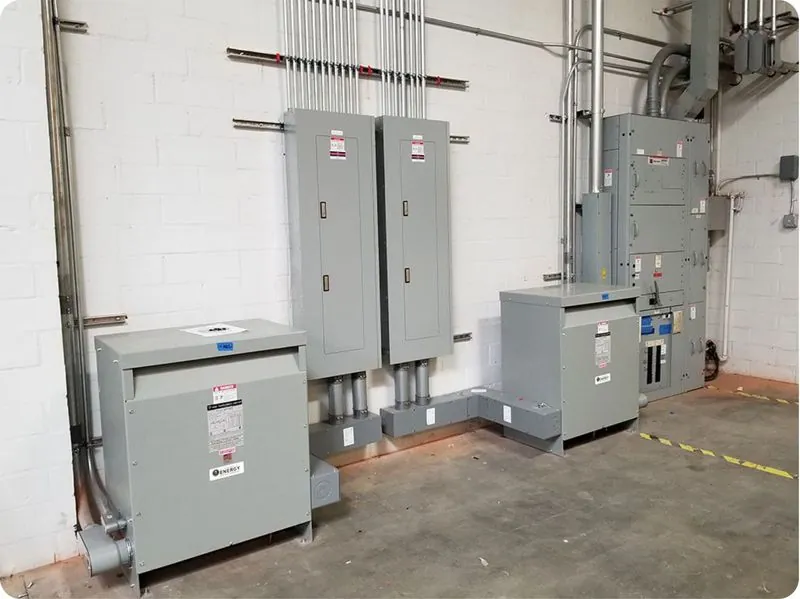 utility room with grey switchgear cabinets, transformers and conduit