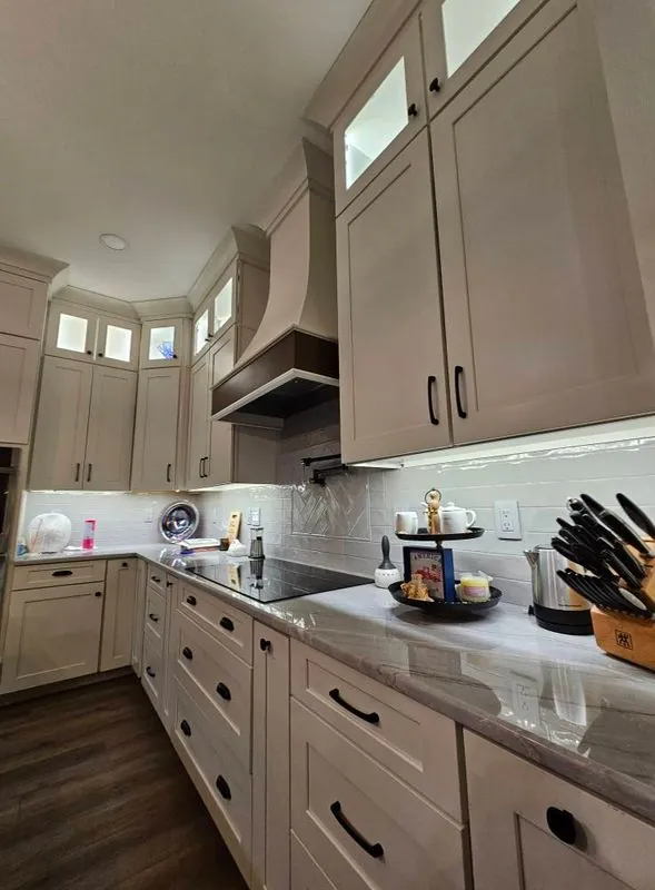 greige kitchen with tall cabinets, range hood and under-cabinet lighting