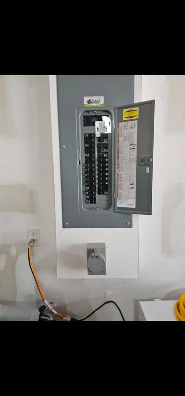 open residential breaker panel on a white wall with wiring below