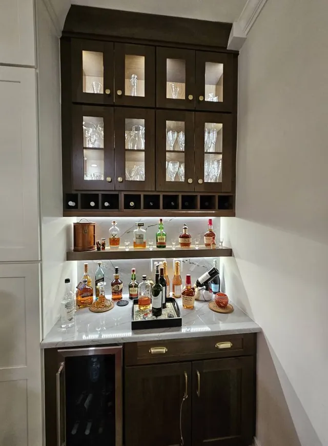 Lit glass-front cabinets over a bar
